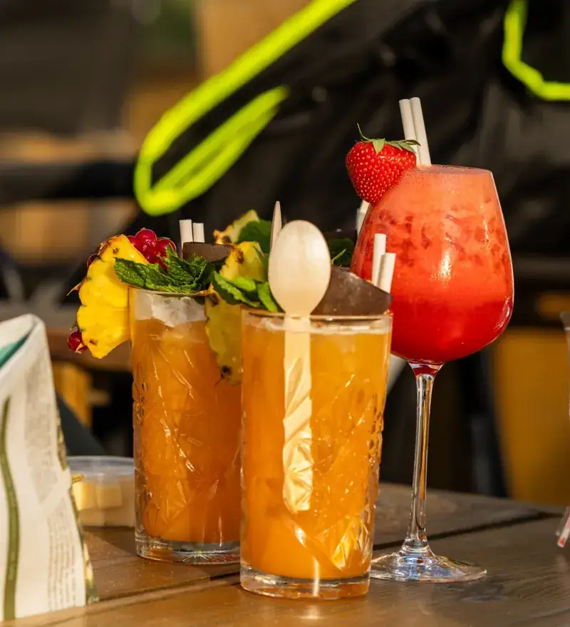 Twee cocktails met vers fruit en een rietje op een houten tafel