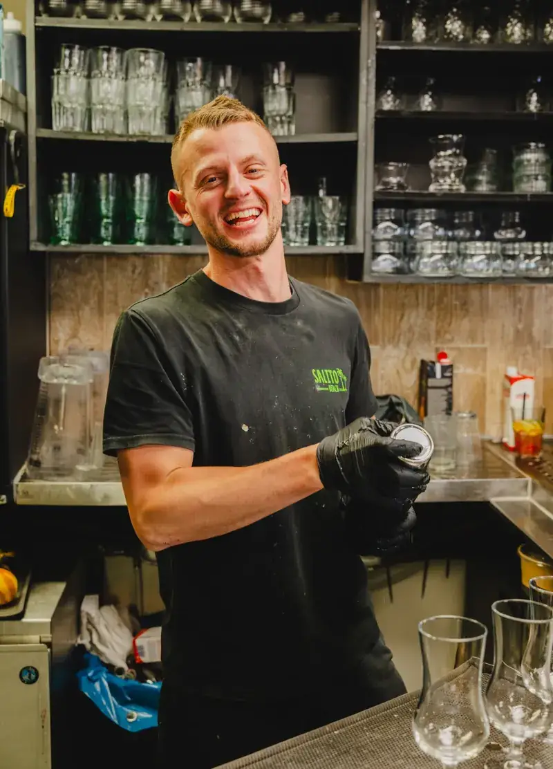 Lachende bartender achter de bar van Salito Beach