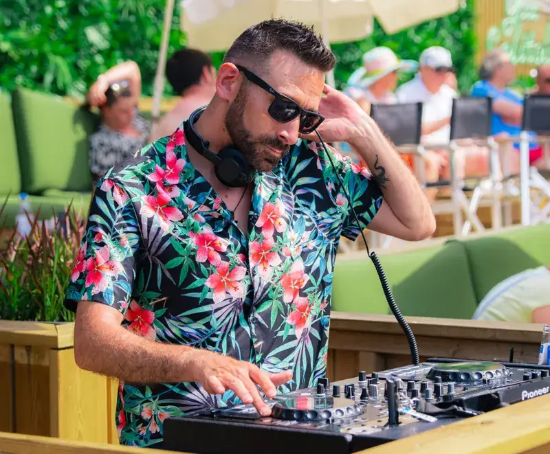 DJ in bloemenhemd achter de draaitafels op het terras