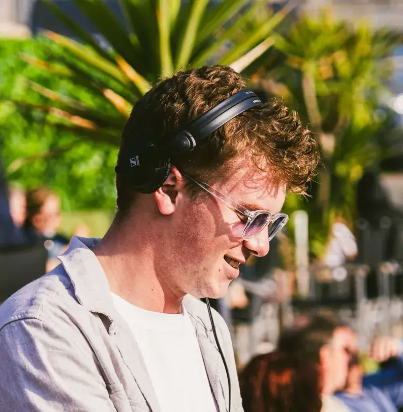 DJ met koptelefoon tussen de palmbladeren