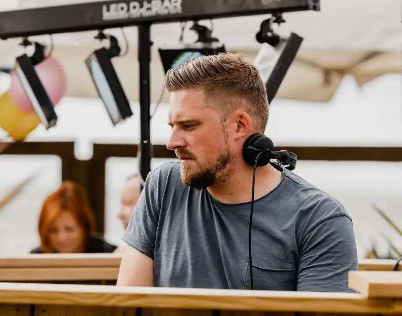 DJ achter de booth onder een parasol