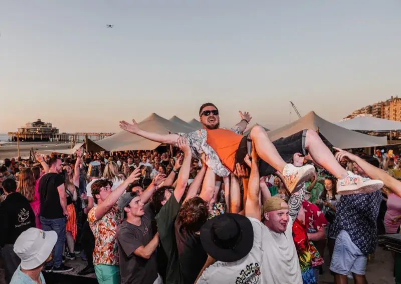 Feestganger crowdsurft boven het publiek bij zonsondergang